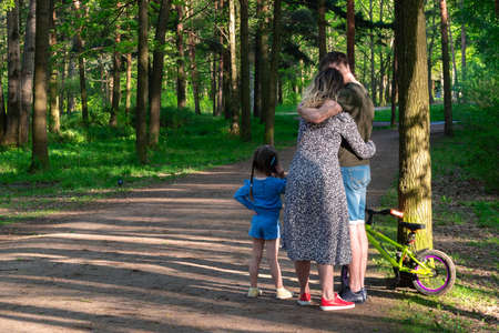 a young family with a child is standing together in the park. view from the back.の写真素材