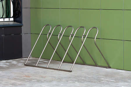 Empty bike parking stand by the green wall. High quality photo