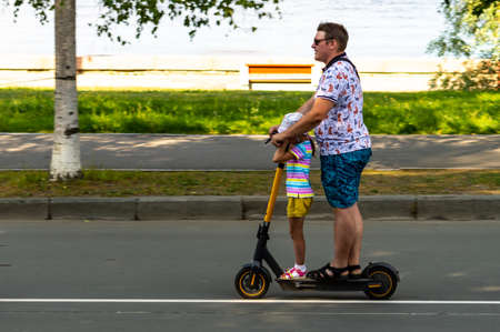 a man rides an electric scooter with his little daughter. Motion blurのeditorial素材
