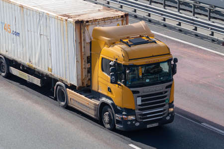 a truck carries a rusty container along the highwayのeditorial素材