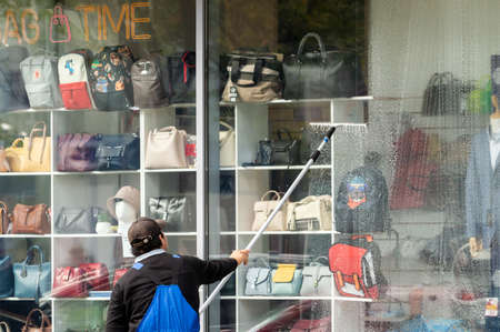 Saint Petersburg, Russia - 7 September 2021. a view from the back of a worker washing a shop window.のeditorial素材