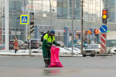 man janitor collects garbage in a large bagのeditorial素材