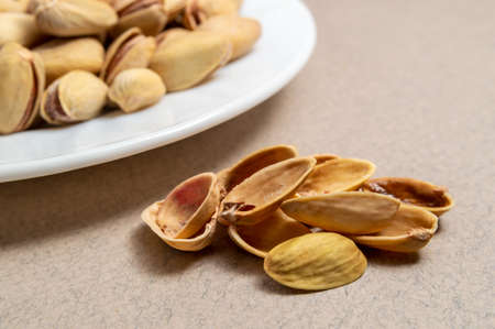 empty pistachios shell next to a plate of pistachios
