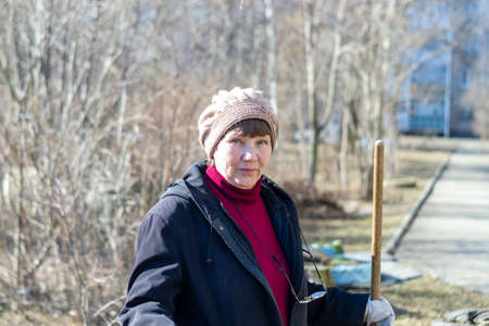 portrait of an elderly woman with a broom on the street.の写真素材