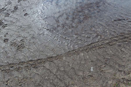 Abstract background with puddle and footprints on mud