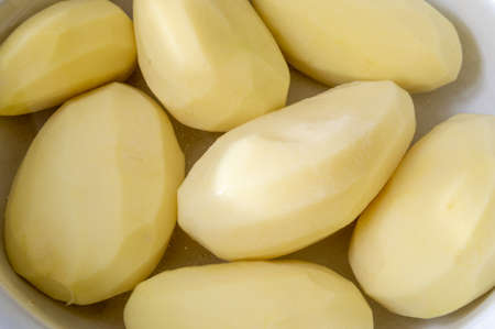 peeled raw potatoes in a bowlの写真素材