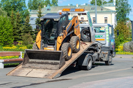 Petrozavodsk, Russia - June 6, 2022. Skid steer loader on a tow truck. tow truck with sliding platformのeditorial素材
