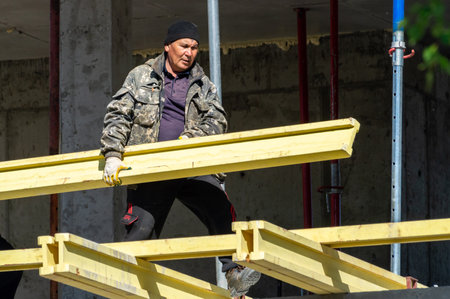 Petrozavodsk, Russia - 6 June 2022. the builder carries a wooden I-beam