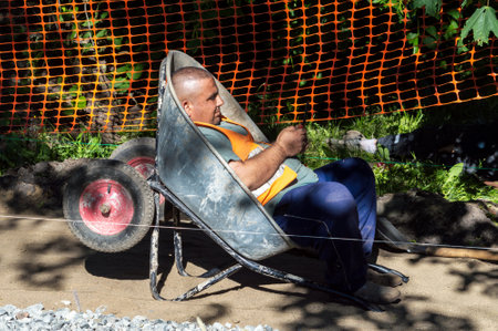 Petrozavodsk, Russia - 28 June 2022. A road worker rests in a wheelbarrowのeditorial素材