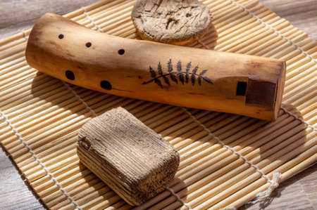 A wooden ethnic wind instrument on a bamboo mat. selective focus
