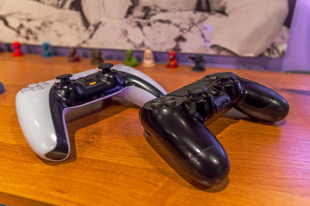Petrozavodsk, Russia - 9 July 2022. two Playstation 5 gamepads on a wooden table. selective focusのeditorial素材