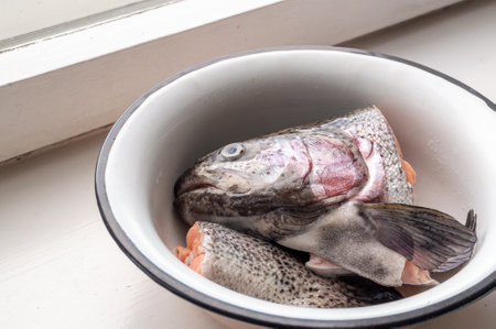Raw trout head and tail in a bowl.