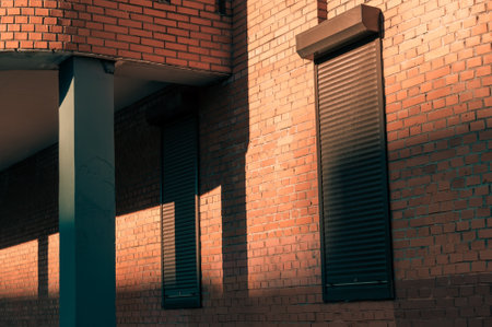 narrow windows closed with roller shutters. the facade of the building illuminated by the sunriseの写真素材