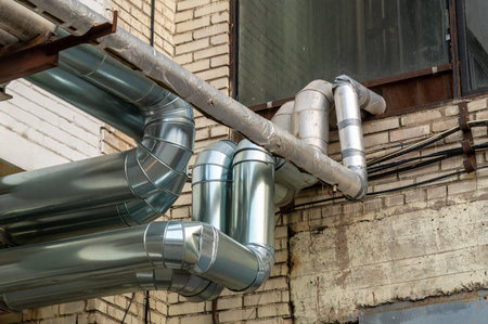 Shiny metal pipes on the facade of a brick industrial building