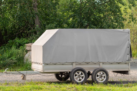 Car trailer on side of road against background of forest