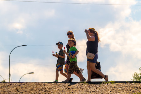 Petrozavodsk, Russia - 8 August 2023. Two women with children against background of summer skyのeditorial素材