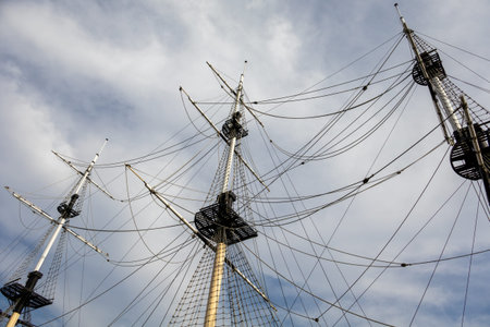A large ship with three masts and a sail. The sails are tattered and the ship appears to be old