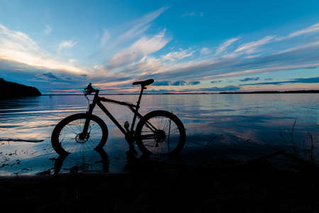 evening silhouette of a mountain bike on the lake with a beautiful sunsetの写真素材