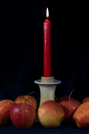 candle holder with a burnt down candle. Red apples and a burning candle on velor blue fabric surface.の写真素材
