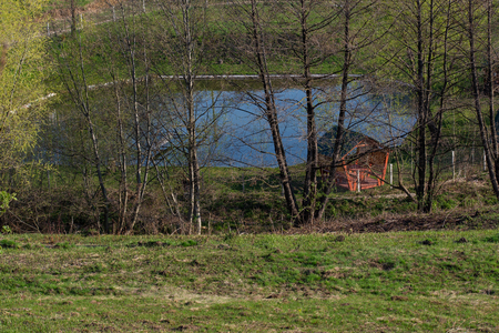 Wooden holiday cottage with an arbor and access to the water on the shore of a lake in the shade of trees. A place for relaxation and recreation at natureの写真素材