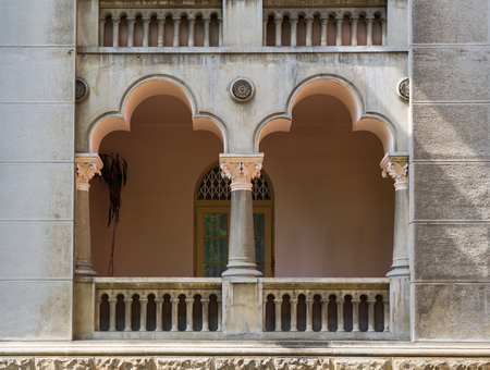 Balcony of an old residential building with concrete railing and arched columns with patterns and stucco. Austrian house of the 19th century in Chernivtsi city.の写真素材