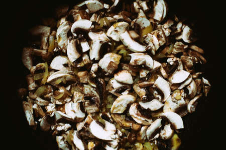 Sliced champignon mushrooms fried with onions on a dark backgroundの写真素材