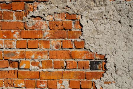 Fragment of an old weathered brick wall with peeling plasterの写真素材