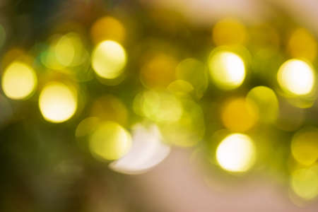 defocused Christmas lights in the form of bokeh of yellow and green shadesの写真素材