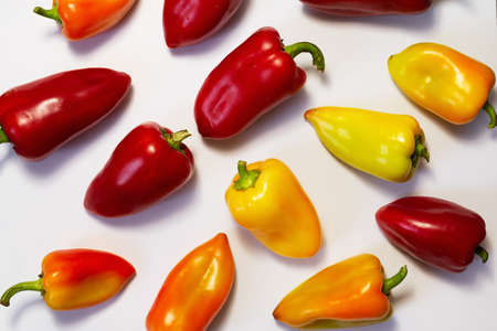 Different colors sweet peppers laid out on a white surface