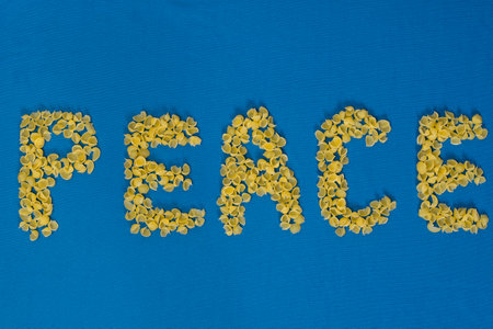 Word peace laid out from humanitarian aid pasta on blue fabric. Colors of the flag of Ukraine. The...
