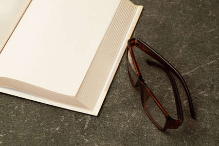 A designer glasses with an open book on a granite coffee table.の写真素材
