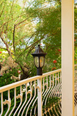 View from the balcony with painted wrought iron railings and a night lamp to the courtyard garden