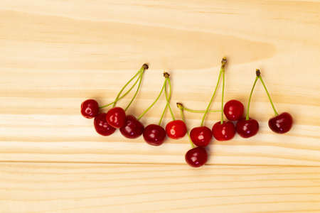 Several red cherries on a wooden surface