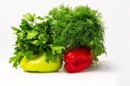Two red and green sweet peppers with green parsley and dill with white backgroundの写真素材