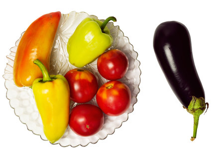 Assorted vegetables from fresh eggplants, bell peppers and top view tomatoes. Isolated vegetables in a glass plate on a white background.の写真素材