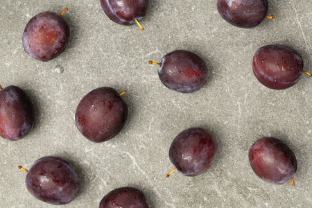 Pattern of ripe plums on gray granite surface with top viewの写真素材