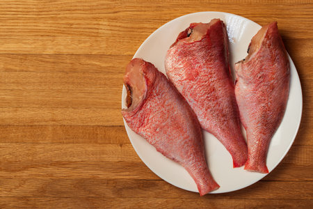 Whole raw red snapper or sea bass on a plate. natural wooden background. view from above. copy space