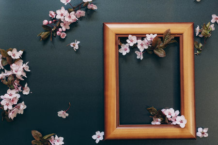 A blank of a rectangular wooden frame decorated with sakura flowers with a black back surface . spring festive backgroundの写真素材