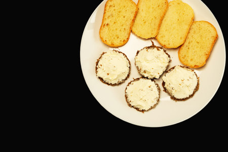 Homemade sandwich with toasted bread slices and rye bread with cheese paste on a white plate. Black background. flat lay. top viewの写真素材