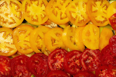 Slices of red and yellow tomatoes on the kitchen table top view.の写真素材