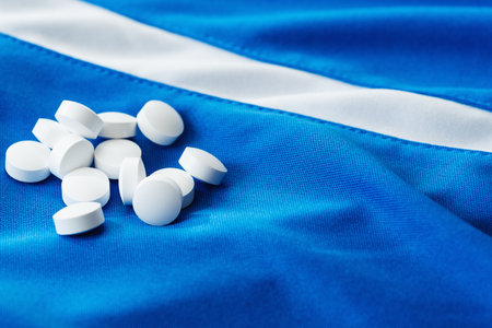 White health tablets are scattered on the fabric.の写真素材