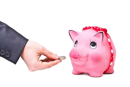 Hand gives coin to moneybox isolated on white backgroundの写真素材
