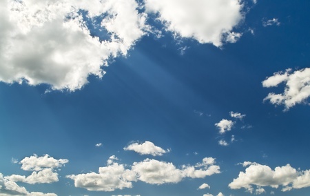 Bright blue cloudy sky with sunbeams from cloudsの写真素材