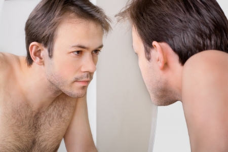 Man checks his reflection in the mirror in early morningの写真素材