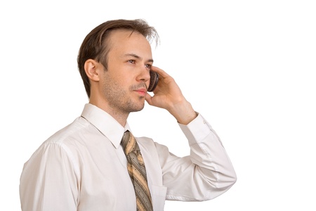 Businessman in white shirt talks on phone with serious face isolated on whiteの写真素材