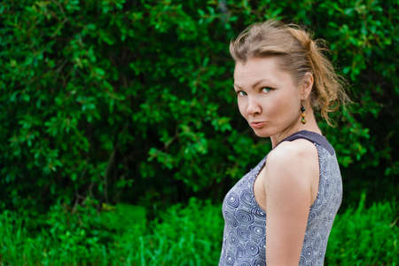 Capricious woman against green summer background looks to cameraの写真素材