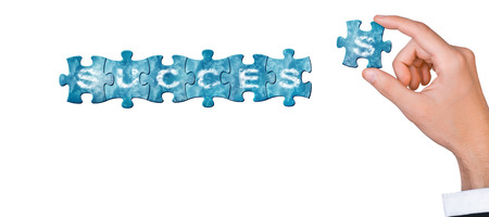 Concept of success - hand connects puzzle piece to build word success