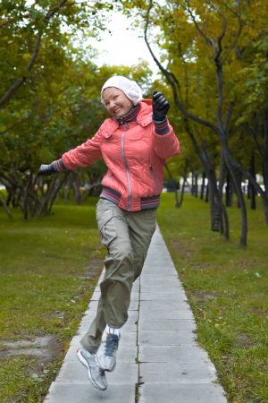 Yound woman in red jacket jumps and have a fun in the parkの写真素材