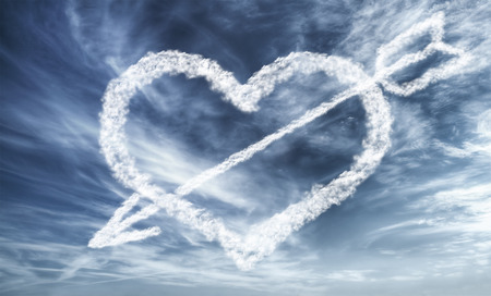 Bright blue dramatic sky with cloudy heart and arrow - love conceptの写真素材