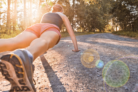 Young sport woman does pushups on the summer forest roadの写真素材